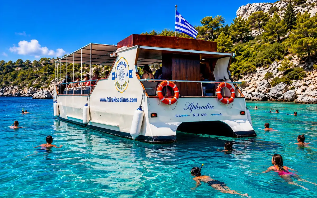 A small wooden excursion boat anchored in a clear turquoise bay on the east coast of Rhodes