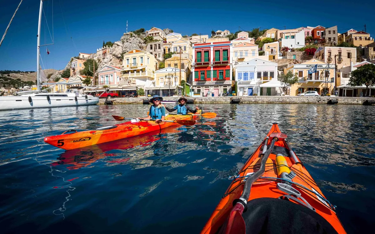 Pastel neoclassical houses stacked above a narrow harbour on the island of Symi in the Dodecanese