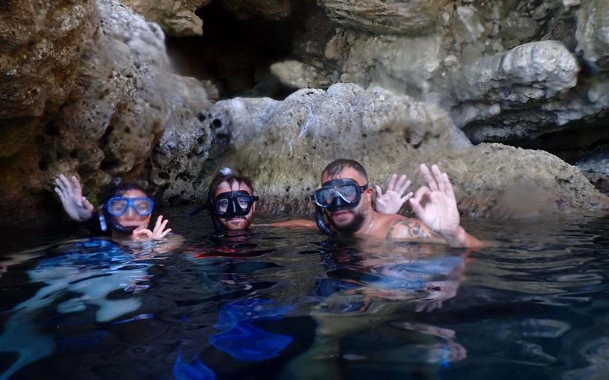 Snorkelers at the surface of clear water beside a boat off the coast of Rhodes